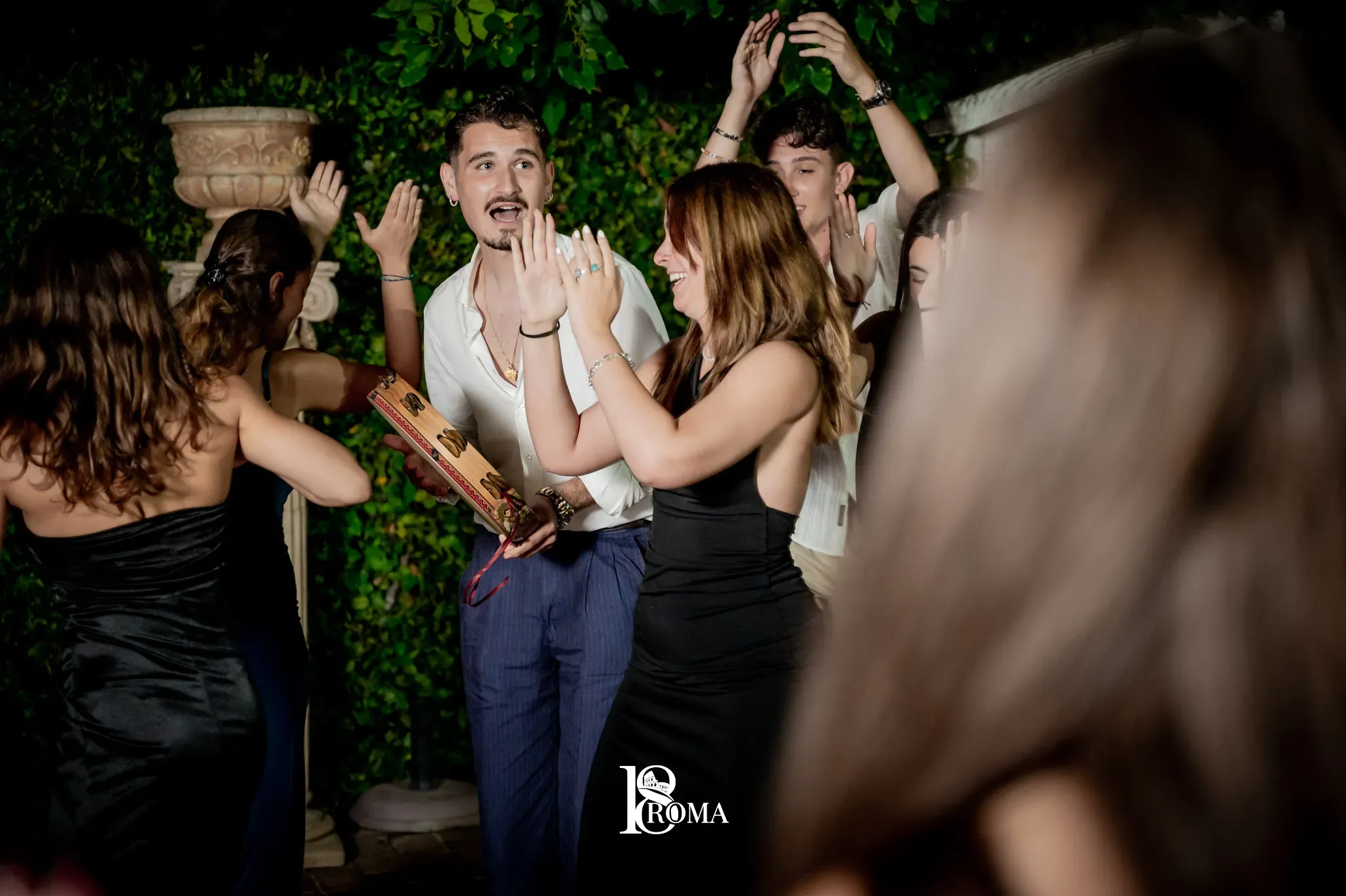 Festeggiata dei 18 anni che taglia la torta circondata dagli amici durante la festa